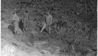 Soldiers inspect a crater caused by the Japanese attack at Fort Stevens. 