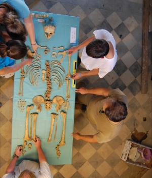 Students examine the skeleton of a young man excavated at Badia Pozzeveri. (Credit: Ohio State University)