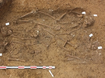 A group of four skeletons buried head-to-toe in a grave. (Credit: Frederic Metenier/Inrap)