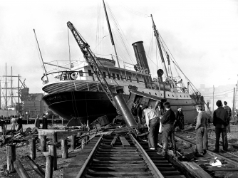 A ship uprooted from the water lays across railroad tracks in New London, Connecticut. (Credit: Getty Images)