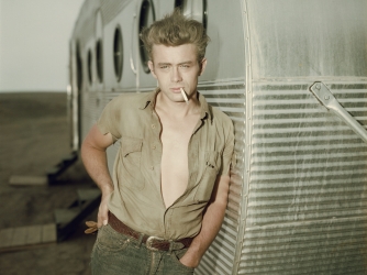 James Dean leaning against a dressing room trailer on the set of director George Stevens's film, 'Giant,' in 1955. (Credit: Hulton Archive/Getty Images)