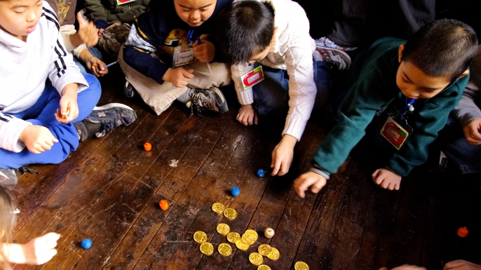Second grade students play with dreidels and chocolate gold coins. (Credit: Stephen Chernin/Getty Images)