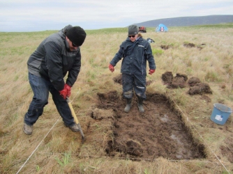 Chase Childs (L) & Sarah Parcak (R) removing upper grass layer. (Credit: Greg Mumford)
