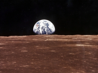 A view of the Earth appears over the Lunar horizon as the Apollo 11 Command Module comes into view. (Credit: NASA/Newsmakers)