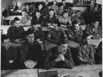 View of the audience, seated in rows and listening during a demolition class, in England, 1944. Office of Strategic Services. (Credit: Public Domain)