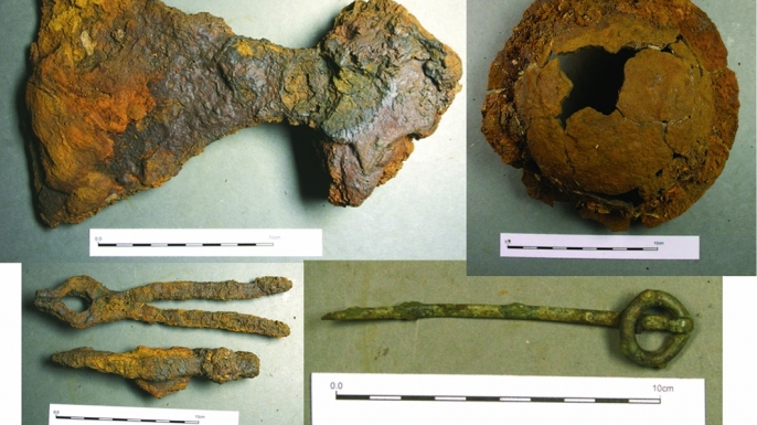Some of the artifacts recovered from the burial site (clockwise from the top left): broad-bladed axe, shield boss, ringed pin and the hammer and tongs (Credit: Pieta Greaves/AOC Archaeology).