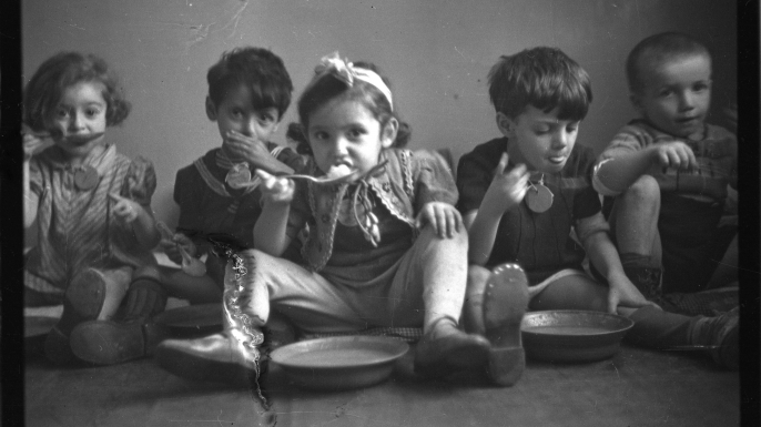 Five children siting on floor and eating, 1940-1944.