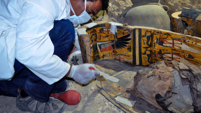 A member of an Egyptian archaeological team works on a wooden coffin discovered in a 3,500-year-old tomb in the Draa Abul Nagaa necropolis. (Credit: STRINGER/AFP/Getty Images)
