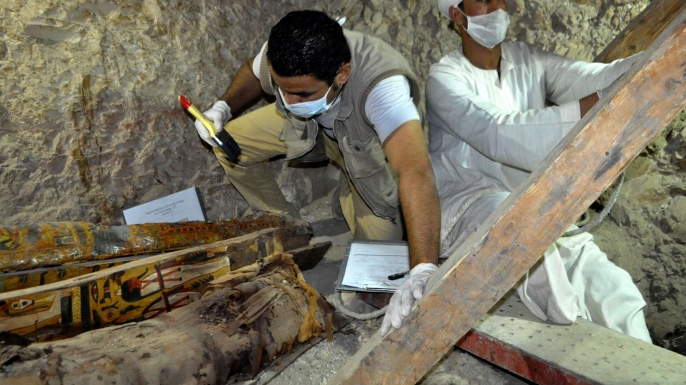 Members of an Egyptian archaeological team work on a wooden coffin discovered in a 3,500-year-old tomb in the Draa Abul Nagaa necropolis. (Credit: STRINGER/AFP/Getty Images)