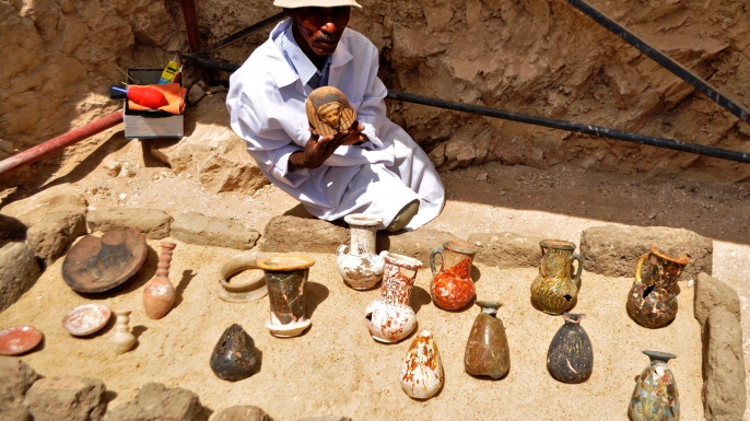 A member of an Egyptian archaeological team shows artifacts discovered in a 3,500-year-old tomb in the Draa Abul Nagaa necropolis. (Credit: STRINGER/AFP/Getty Images)