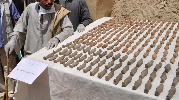 Members of an Egyptian archaeological team stand near artifacts, known as Ushabtis, discovered in a 3,500-year-old tomb in the Draa Abul Nagaa necropolis. (Credit: STRINGER/AFP/Getty Images)