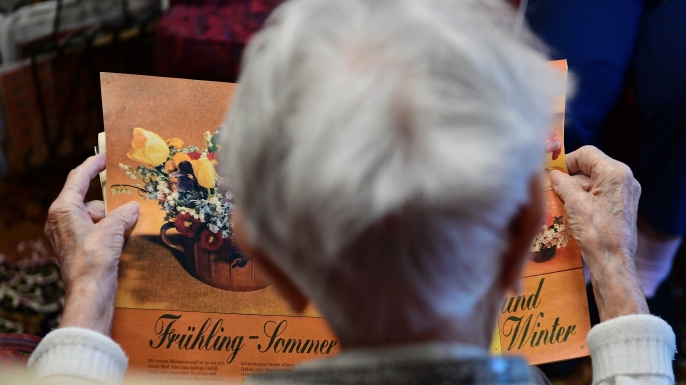 A resident looks at a magazine inside an east German 60s lounge at a nursing home in Dresden, Germany. (Credit: Tobias Schwarz/AFP/Getty Images)