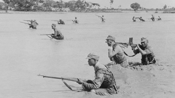 Holding their lines to the utmost against Japanese, the defenders refused to retreat when the Yellow River began flooding. Here, through the muddy stream, a Chinese advance guard braves flood and enemy fire. (Credit: Bettmann/Getty Images)