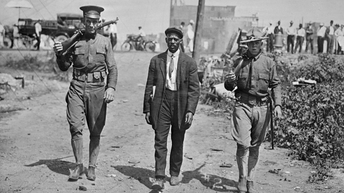 Two National Guard soldiers escort a black man in the aftermath of the East St. Louis Riots.