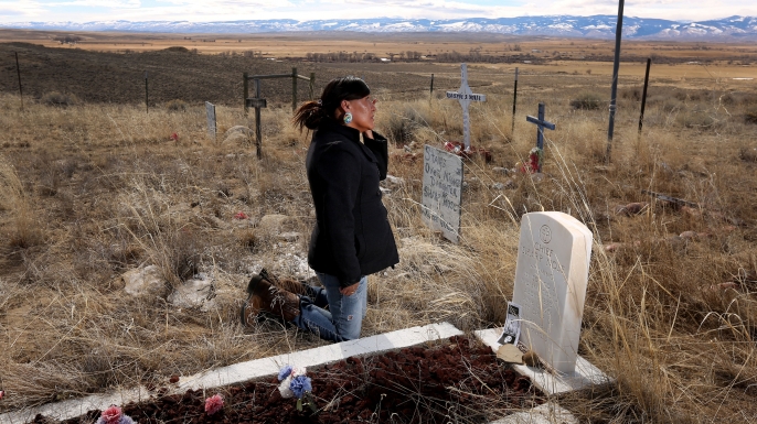 Yufna Soldier Wolf wipes away tears while kneeling at the grave of her great-grandfather, Chief Sharp Nose of the Northern Arapaho Tribe, at the family cemetery on the Wind River Reservation near Riverton, Wyo. Soldier Wolf is seeking the remains of her great-uncle Little Chief, who died while attending Carlisle Indian School in Carlisle, Pennsylvania. (Credit: Dan Cepeda/The Casper Star-Tribune/AP Photo)