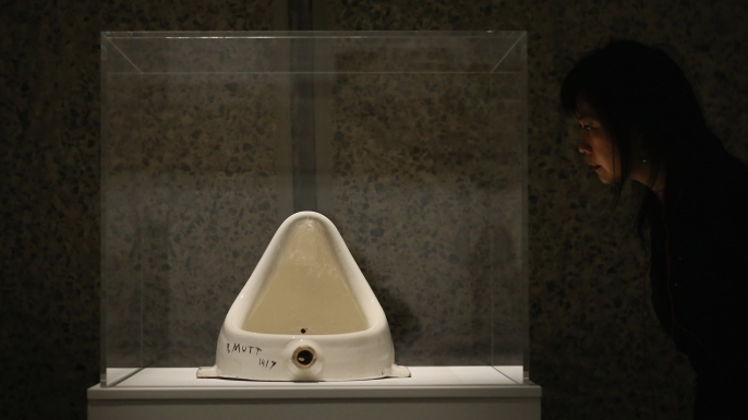 A woman looks at 'Fountain' by Marcel Duchamp during a press preview of an exhibition at the Barbican Art Gallery in London, England. (Credit: Dan Kitwood/Getty Images)