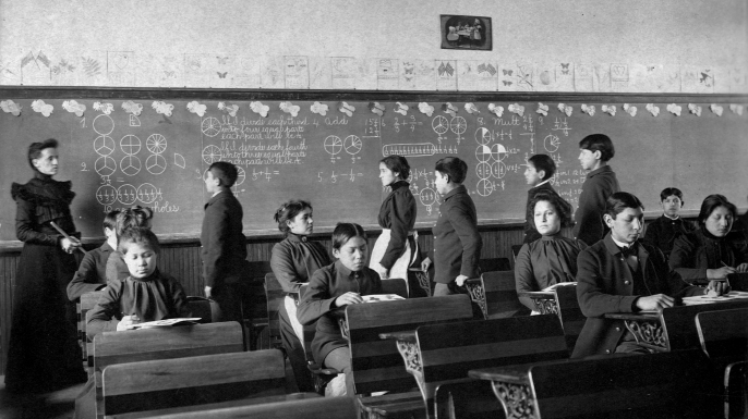 Native Amercian students study at their desks and line up at the chalkboard during class at the Carlisle Indian School in Carlisle, Pennyslvania. (Credit: Library of Congress/Corbis/VCG via Getty Images)