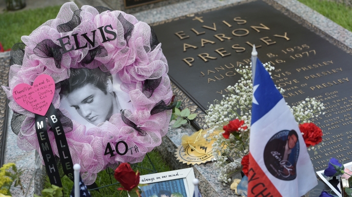 Tributes and momentoes are seen next to the marker for Elvis Presley in the Meditation Garden where he is buried alongside his parents and grandmother at his Graceland mansion in August 2017, the 40th anniversary of his death. (Credit: Mandel Ngan/AFP/Getty Images)