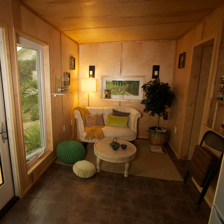 Decorated with wooden walls and a love seat, this living tiny house room gives off the calming zen atmosphere that Phillise wanted.