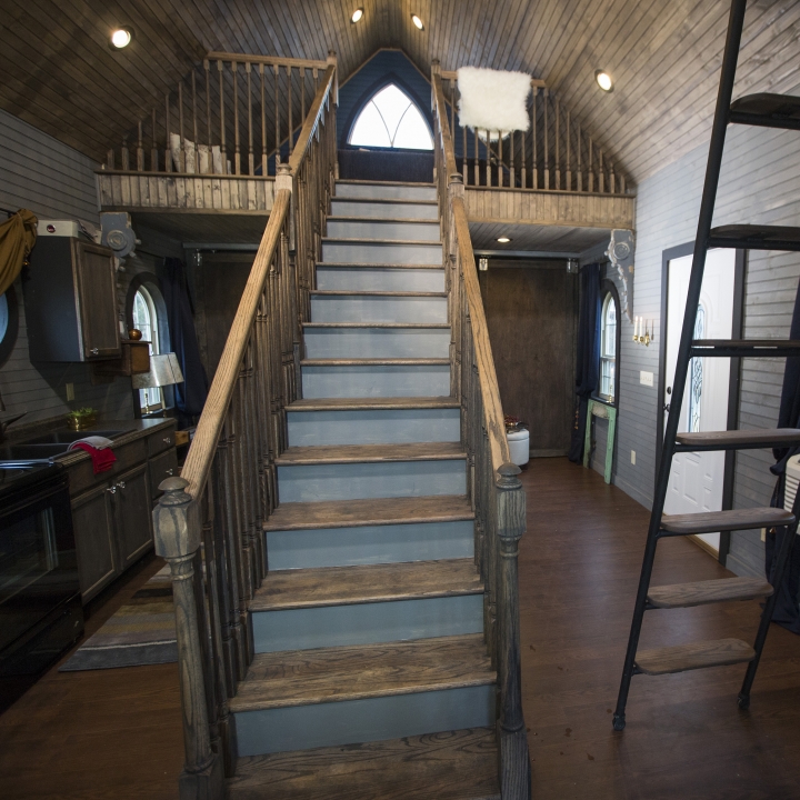 A grand staircase is the focal point of this medieval yet modern tiny home.