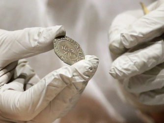 Hatchfield holding the 1652 "Pine Tree Shilling" found in the capsule (Credit: Bostom Museum of Fine Arts)