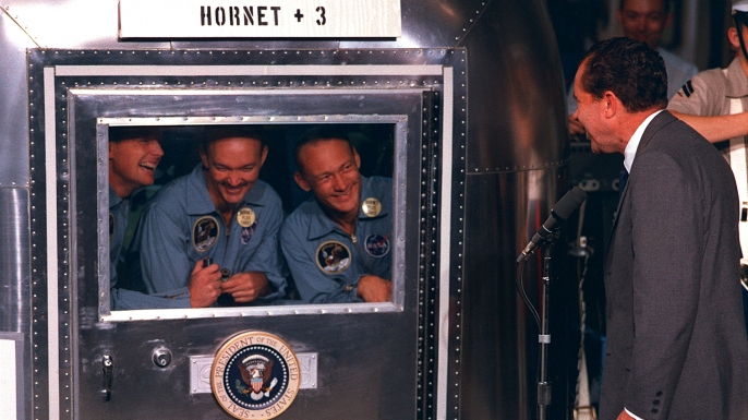 President Richard M. Nixon was in the central Pacific recovery area to welcome the Apollo 11 astronauts. Already confined to the Mobile Quarantine Facility (MQF) are (left to right) Neil A. Armstrong, commander; Michael Collins, command module pilot; and Edwin E. ("Buzz") Aldrin Jr., lunar module pilot. (Credit: NASA)