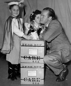 Bob Hope in Poland with children dressed in European costumes. (Credit: CARE)