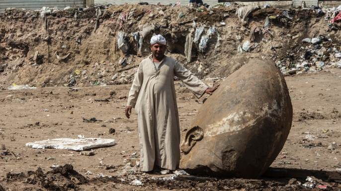 An Egyptian worker stands next to the head of the statue. (Credit: KHALED DESOUKI/AFP/Getty Images)