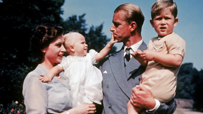 Queen Elizabeth holding daughter Anne and Prince Philip holding son Charles.