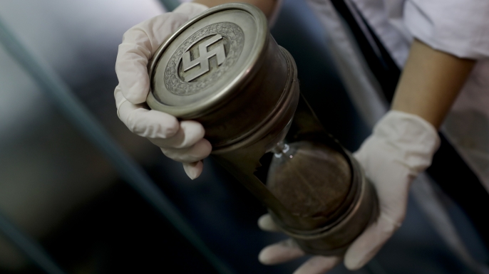 A member of the federal police holds an hourglass with Nazi markings at the Interpol headquarters in Buenos Aires, Argentina. (Credit: Natacha Pisarenko/ AP Photo)