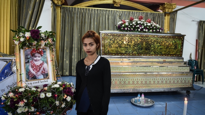 Jiranuch Trirat, 22, stands in front of the coffin of her slain 11-month-old daughter Natalie at a temple in Phuket on April 27, 2017. (Credit: LILLIAN SUWANRUMPHA/AFP/Getty Images)