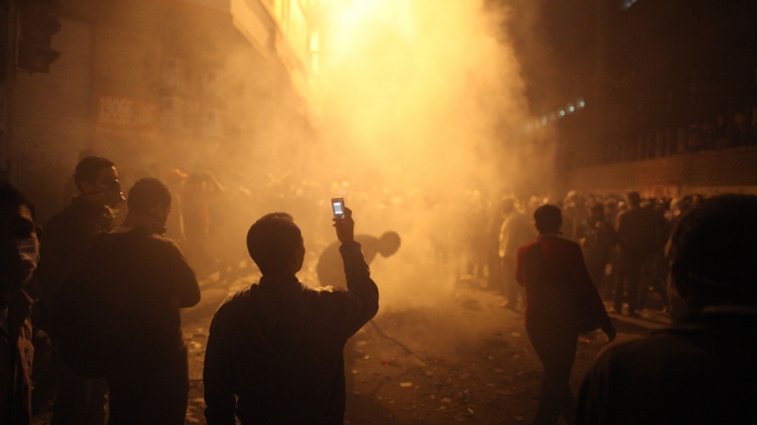 A youth films the aftermath of a tear gas volley fired by police on protestors in Muhammed Mahmoud Street near Tahrir Square on November 23, 2011 in Cairo, Egypt. (Credit: Peter Macdiarmid/Getty Images)