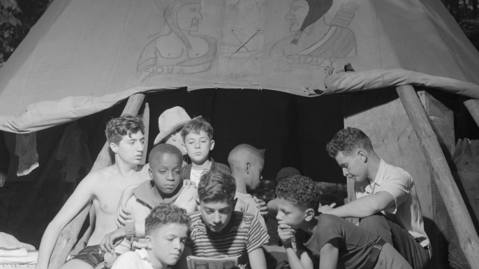 Boys sharing a comic book at the racially integrated Camp Nathan Hale in Southfields, NY, 1943. (Credit: Gordon Parks/Everett Collection Inc/Alamy Stock Photo)
