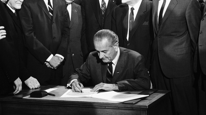 On April 11, 1968 President Lyndon Johnson signs the Civil Rights bill while seated at a table surrounded by members of Congress, Washington DC. (Credit: Warren Leffler/Underwood Archives/Getty Images)