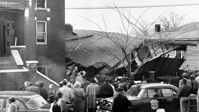 Onlookers surround the home of Rev. Fred Shuttleworth, which was destroyed by a dynamite blast. The Reverend's wife and two children were injured in the explosion. (Credit: Bettmann/Getty Images)