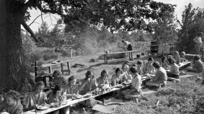 The Junior Girl Scouts at Camp Merritt prepare their own lunches, and enjoy them too, East Hartland, Connecticut, mid 1920s. (Credit: Underwood Archives/Getty Images)
