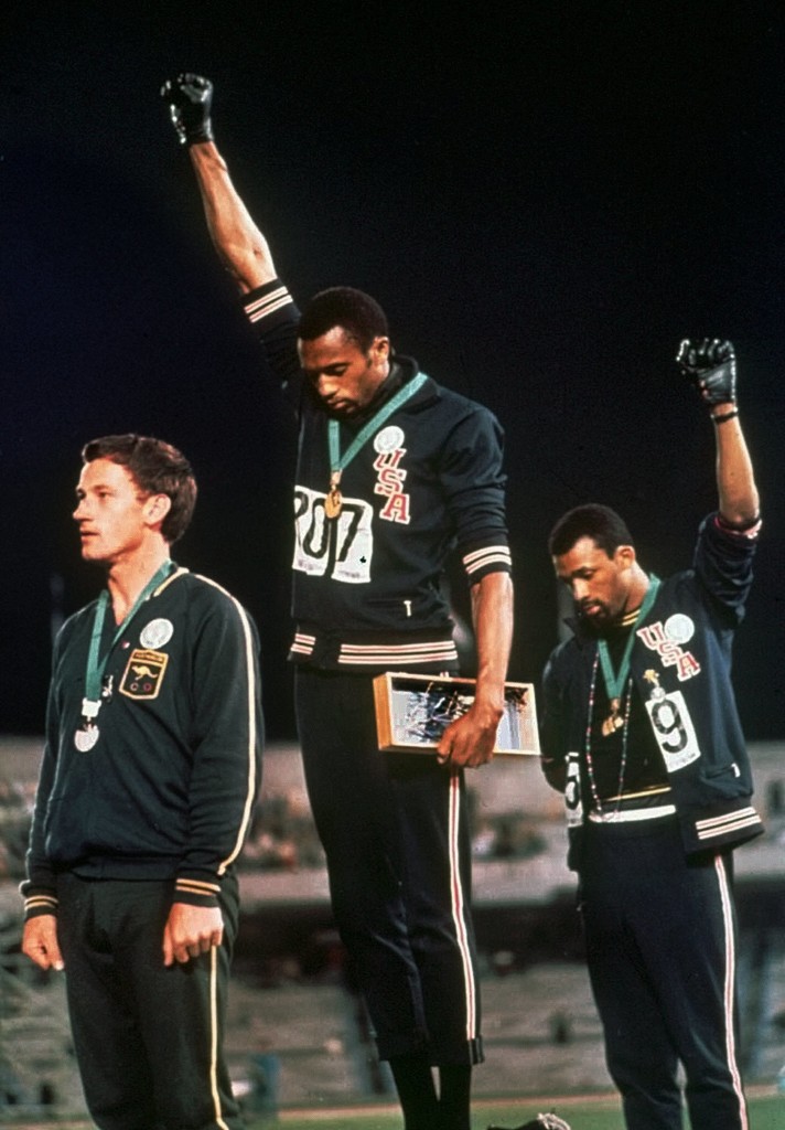 U.S. athletes Tommie Smith, center, and John Carlos raise gloved hands skyward during the playing of the Star Spangled Banner after Smith received the gold and Carlos the bronze for the 200 meter run at the Summer Olympic Games in Mexico City, 1968. (Credit: AP Photo)