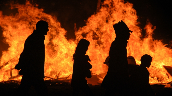 A family is silhouetted by a bonfire on Halloween night.