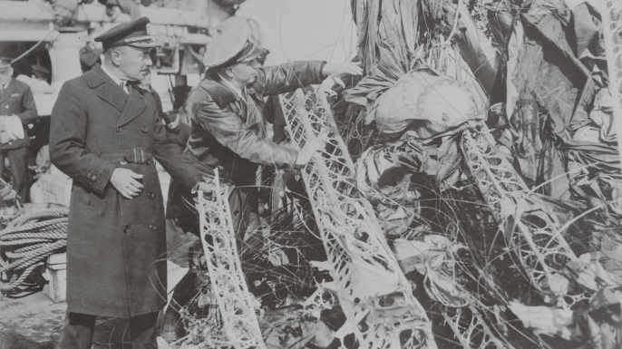 Captain R.A. White, (left) in charge of salvage operations, and Lieut. Commander J.L. Fisher, air expert of Lakehurst, N.J., examine the huge mass of wreckage of the U.S. dirigible Akron, after it had been drawn from the ocean by the U.S.S. Falcon salvage ship. (Credit: Bettmann/Getty Images)