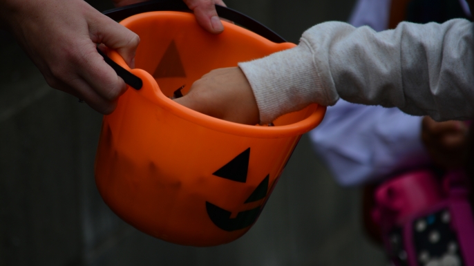 Child's hand picking candy from a Halloween basket