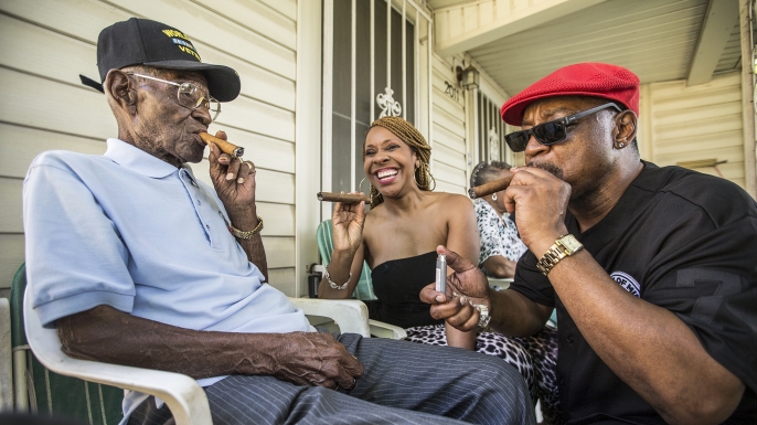 Richard Overton smoking a cigar with a few neighborhood friends Donna Shorts and Martin Wilford in Austin, Texas, 2015. (Credit: Ricardo B. Brazziell/Austin American-Statesman via AP)