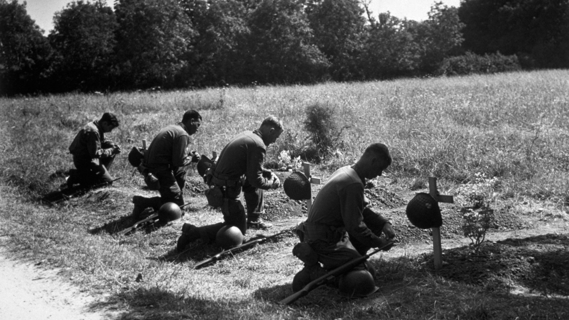 American soldiers kneel in homage at the graves of their dead comrades in northern France, 1944. (Credit: Fred Ramage/Keystone/Getty Images)