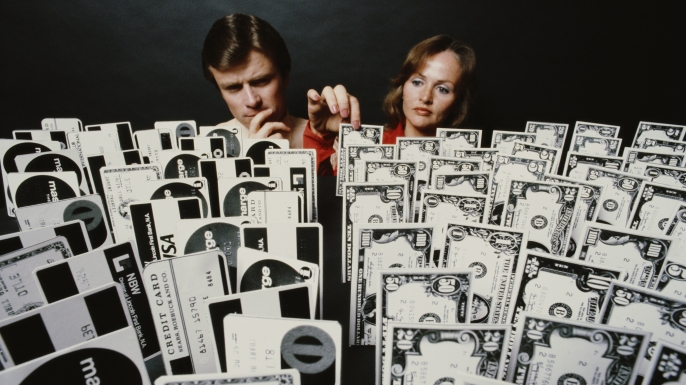 A man and a woman overlooking an array of credit cards and money, 1979. (Credit: Alfred Gescheidt/Getty Images)