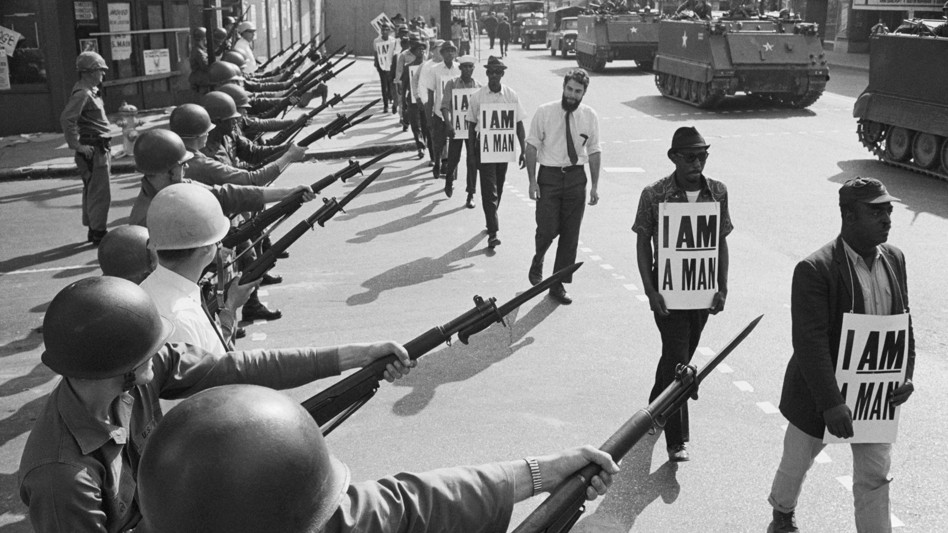 U.S. National Guard troops blocking off a street while striking Memphis sanitation workers march by, wearing placards reading, 'I Am A Man' on March 29, 1968. King was killed on the eve of a second march to support the sanitation workers. (Credit: Bettmann Archive/Getty Images)