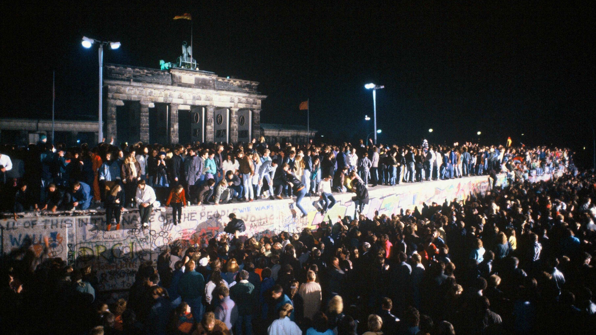 Thousands of celebrants climb atop the Berlin Wall in front of Brandenburg Gate on the night of November 9th, 1989. Crowds had flocked to the border crossings after a botched news announcement spread rapidly that the East German Government would start granting exit visas to anyone who wanted to go to the West. (Credit: Robert Wallis/Corbis via Getty Images)